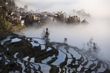 China, Yunnan, Yuanyang, Bedeckte Reisterrassen und Dorf - JBAF000090