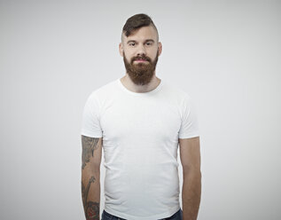 Portrait of smiling young man with shaved head, full beard and tattoo - RH000281