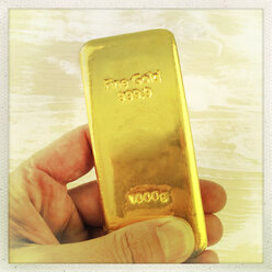 Männliche Hand mit 1 kg Goldbarren - DRF000504