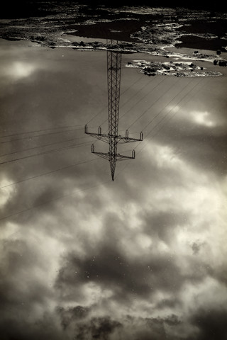 Power pylon reflecting in water surface stock photo