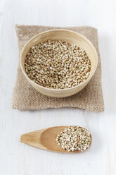 Bowl and wooden shovel of buckwheat grains on white wooden table - EVGF000430