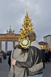 Deutschland, Berlin, junges Paar betrachtet Arm in Arm das Brandenburger Tor und den beleuchteten Weihnachtsbaum - CLPF000069