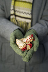 Young woman with gloves holding Christmas decoration, partial view - CLPF000066