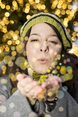 Porträt einer jungen Frau, die goldenen Glitter bläst, lizenzfreies Stockfoto