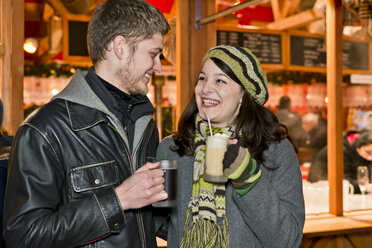 Deutschland, Berlin, glückliches junges Paar mit heißen Getränken auf dem Weihnachtsmarkt - CLPF000054