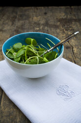 Bowl of winter purslane salad (Claytonia perfoliata) on white cloth napkin and wooden table - LVF000671
