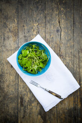 Bowl of winter purslane salad (Claytonia perfoliata) on white cloth napkin and wooden table, view from above - LVF000670
