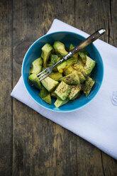 Bowl of avocado salad (Persea americana) on white cloth napkin and wooden table - LVF000665