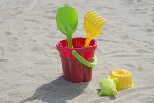 Colourful sandbox toys on sandy beach - CRF002571