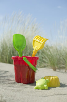 Colourful sandbox toys on sandy beach - CRF002570