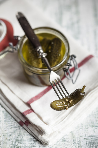 Eingelegte Cornichons in Einmachgläsern und Gabel, lizenzfreies Stockfoto