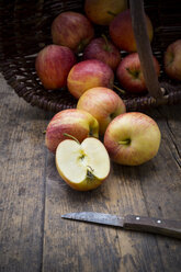 Sliced and whole red apples, basket and kitchen knife on wooden table - LVF000685