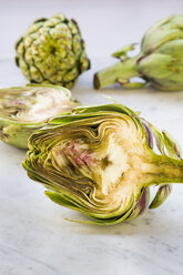 Sliced and whole organic artichokes on white marble - LVF000678