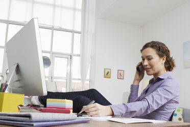 Woman at home at desk with computer and telephone - RBYF000341