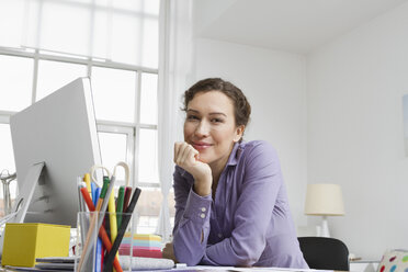 Woman at home sitting at desk with computer - RBYF000342