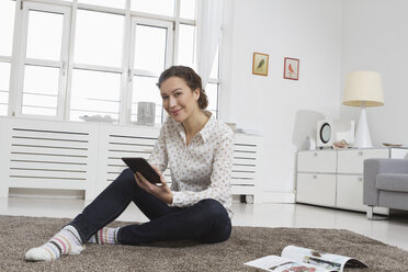 Woman at home reading e-book - RBYF000347