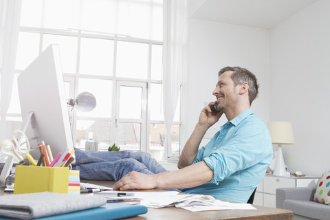 Mann am Schreibtisch beim Telefonieren, lizenzfreies Stockfoto