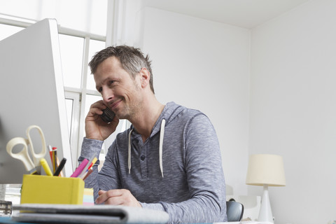 Mann am Schreibtisch beim Telefonieren, lizenzfreies Stockfoto