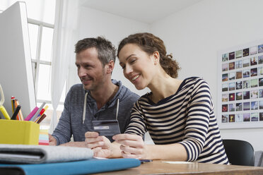 Couple at home sitting at desk shopping online - RBYF000371