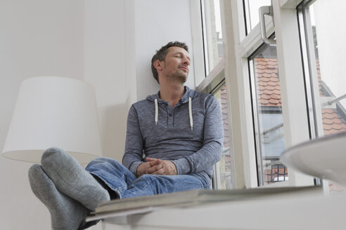 Entspannter Mann auf der Fensterbank sitzend - RBYF000480