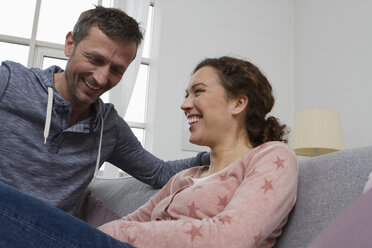 Happy couple sitting on couch - RBYF000402