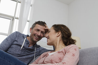 Happy couple sitting on couch - RBYF000403