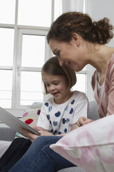 Mutter und Tochter auf der Couch mit Tablet-Computer - RBYF000407