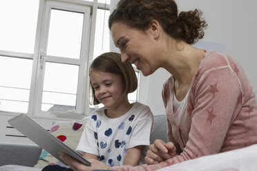 Mother and daughter on couch with tablet computer - RBYF000408