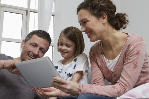 Mutter, Vater und Tochter auf Couch mit Tablet-Computer - RBYF000410