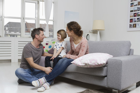 Mutter, Vater und Tochter zu Hause auf der Couch, lizenzfreies Stockfoto