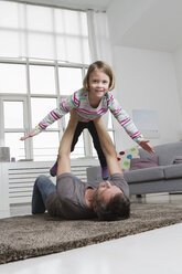 Playful father and daughter in living room - RBYF000488