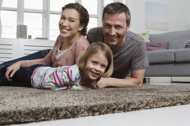 Glückliche Mutter, Vater und Tochter liegen auf dem Teppich im Wohnzimmer - RBYF000489