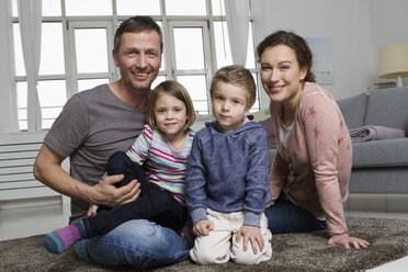 Happy family of four in living room - RBYF000497