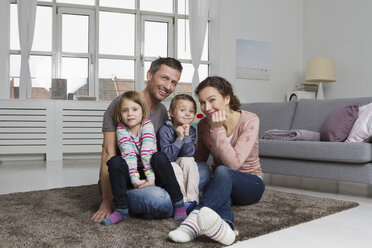 Glückliche vierköpfige Familie im Wohnzimmer - RBYF000499