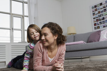 Glückliche Mutter und Tochter liegen auf dem Teppich im Wohnzimmer - RBYF000427