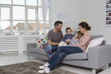 Glückliche vierköpfige Familie auf der Couch sitzend - RBYF000432