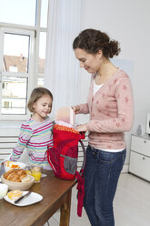 Mutter packt den Rucksack ihrer Tochter am Morgen - RBYF000503