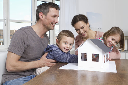 Family of four looking at house model - RBYF000451