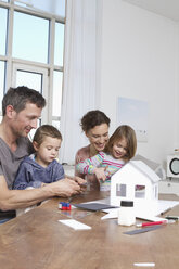 Vierköpfige Familie beim Bau eines Hausmodells - RBYF000453