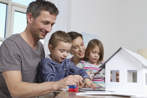 Vierköpfige Familie beim Bau eines Hausmodells, lizenzfreies Stockfoto