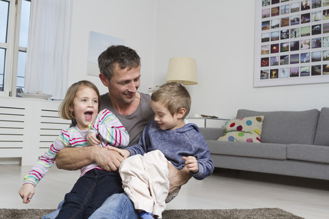 Vater, Tochter und Sohn spielen im Wohnzimmer, lizenzfreies Stockfoto