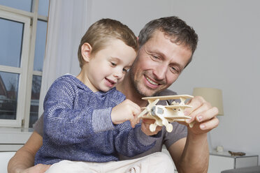 Father and son playing with model airplane - RBYF000463