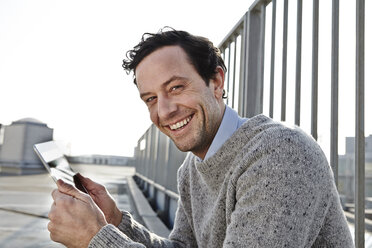 Porträt eines lächelnden Mannes mit Tablet-Computer - FMK000956