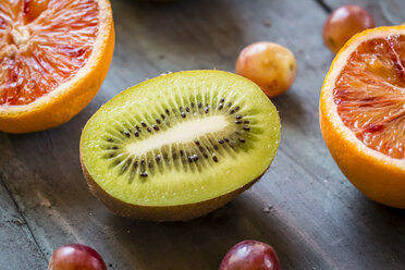 Blue grapes and two halves of blood orange and kiwi on blue wooden ground - SARF000254