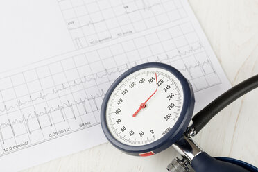 Blutdruckmessgerät mit gedrehter Nadel, im Hintergrund ein EKG, Nahaufnahme - DRF000520