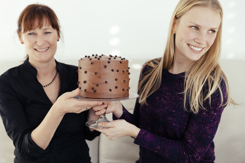 Zwei lächelnde Frauen, die einen Kuchenstand mit Schokoladenkuchen austauschen, lizenzfreies Stockfoto