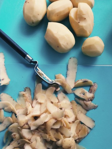 Peeled potatoes and peel on a surface stock photo