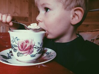 Little boy eating cream from a spoon - MEAF000183