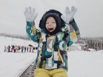 Glücklicher Junge hebt seine Hände im Schnee-Outfit - MEAF000184