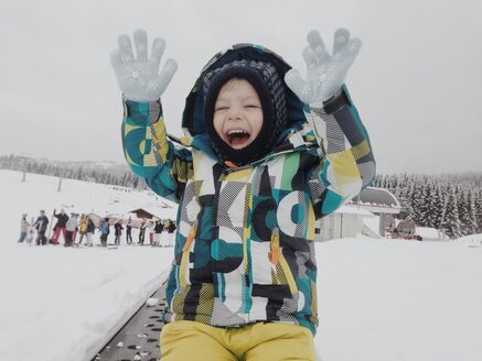 Happy boy lifting his hands in snow outfit - MEAF000184